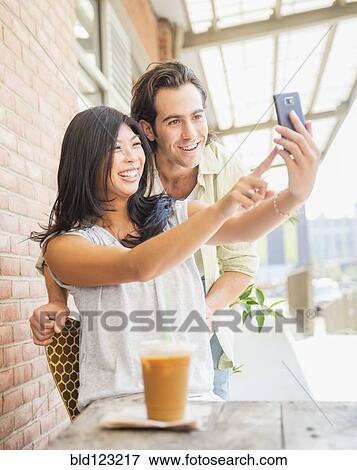 Stock Photo - Couple taking self-portrait at sidewalk cafe. Fotosearch