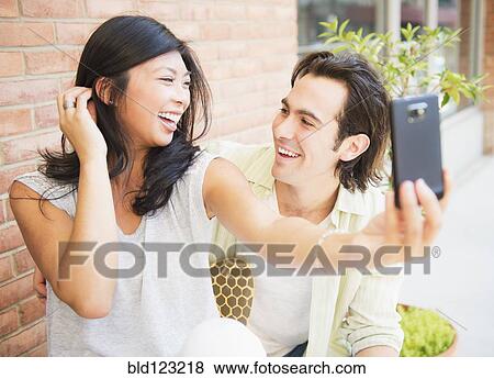 Stock Photo - Couple taking self-portrait at sidewalk cafe. Fotosearch