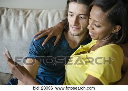 Couple taking self-portrait on sofa View Large Photo Image Stock Photograph - Couple taking self-portrait on sofa. Fotosearch