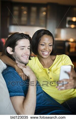 Couple taking self-portrait on sofa View Large Photo Image Stock Photography - Couple taking self-portrait on sofa. Fotosearch