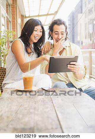 Couple using digital tablet at sidewalk cafe View Large Photo Image Stock Photo - Couple using digital tablet at sidewalk cafe. Fotosearch