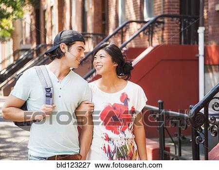 Couple walking on urban sidewalk outside brownstones View Large Photo Image Stock Photo - Couple walking on urban sidewalk outside brownstones. Fotosearch