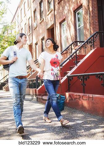 Couple walking on urban sidewalk outside brownstones View Large Photo Image Stock Photo - Couple walking on urban sidewalk outside brownstones. Fotosearch