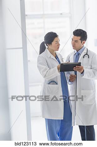 Doctors using digital tablet in hospital corridor View Large Photo Image Stock Image - Doctors using digital tablet in hospital corridor. Fotosearch