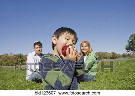 Stock Photo - Hispanic boy eating fruit outdoors. Fotosearch