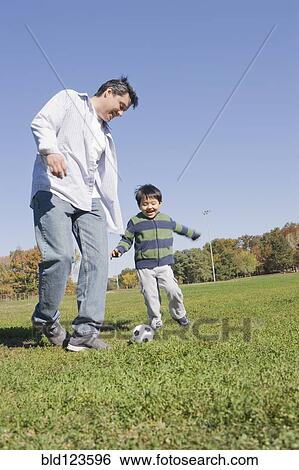 Hispanic father and son playing soccer outdoors View Large Photo Image Stock Photograph - Hispanic father and son playing soccer outdoors. Fotosearch