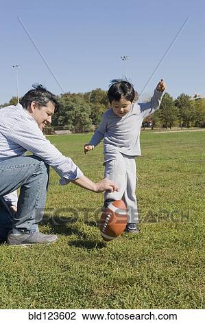 Hispanic father and son playing football outdoors View Large Photo Image Stock Image - Hispanic father and son playing football outdoors. Fotosearch