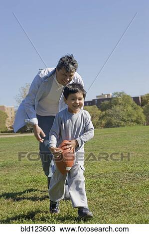 Hispanic father and son playing football outdoors View Large Photo Image Stock Image - Hispanic father and son playing football outdoors. Fotosearch