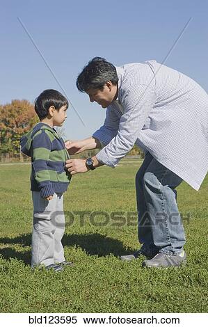 Hispanic father zipping son's sweater in field View Large Photo Image Stock Photography - Hispanic father zipping son's sweater in field. Fotosearch