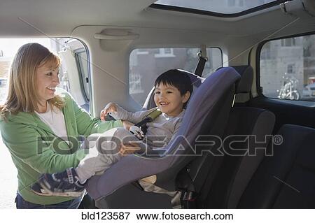 Hispanic woman loading son into car seat View Large Photo Image Stock Photo - Hispanic woman loading son into car seat. Fotosearch
