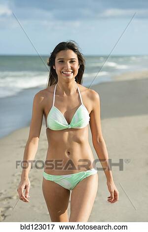 Stock Photo - Hispanic woman walking on beach. Fotosearch
