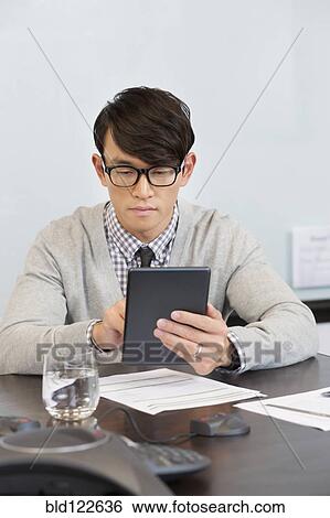 Korean businessman using digital tablet in office View Large Photo Image Stock Photograph - Korean businessman using digital tablet in office. Fotosearch