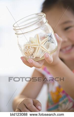 Stock Photo - Korean girl examining starfish in jar. Fotosearch
