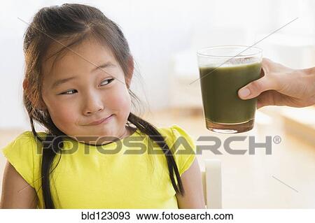 Korean girl frowning at glass of green smoothie View Large Photo Image Stock Image - Korean girl frowning at glass of green smoothie. Fotosearch