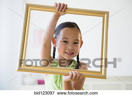 Stock Photo - Korean girl holding empty picture frame. Fotosearch