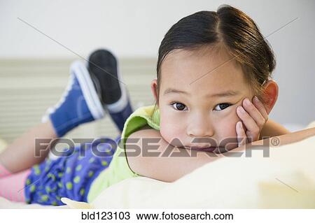 Stock Image - Korean girl laying on bed. Fotosearch