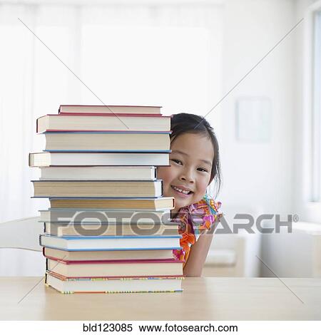 Stock Photography - Korean girl peeking from behind stack of books. Fotosearch