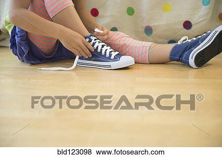 Stock Photo - Korean girl tying shoelaces. Fotosearch