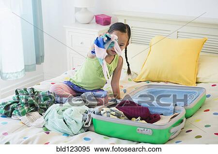Korean girl unpacking suitcase on bed View Large Photo Image Stock Photography - Korean girl unpacking suitcase on bed. Fotosearch