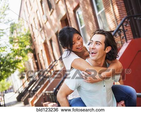Man carrying girlfriend piggyback outside brownstones View Large Photo Image Stock Photograph - Man carrying girlfriend piggyback outside brownstones. Fotosearch