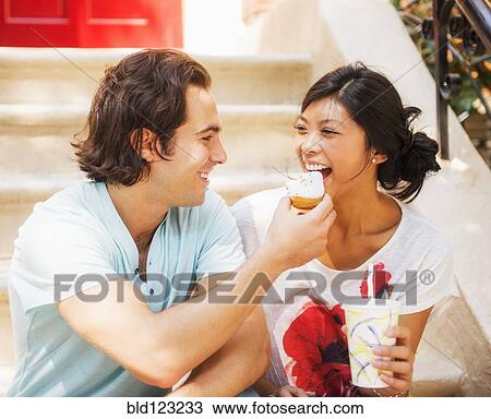 Man feeding donut to girlfriend on front stoop View Large Photo Image Stock Image - Man feeding donut to girlfriend on front stoop. Fotosearch