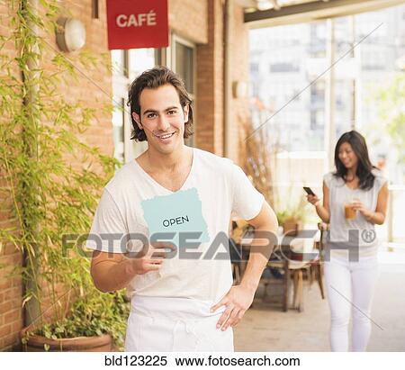 Man holding Open sign by cafe View Large Photo Image Stock Photography - Man holding Open sign by cafe. Fotosearch