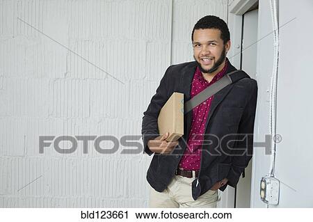 Mixed race businessman holding box in doorway View Large Photo Image Stock Image - Mixed race businessman holding box in doorway. Fotosearch
