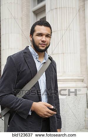 Stock Photo - Mixed race businessman holding cell phone. Fotosearch