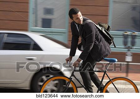 Mixed race businessman riding bicycle on city street View Large Photo Image Picture - Mixed race businessman riding bicycle on city street. Fotosearch