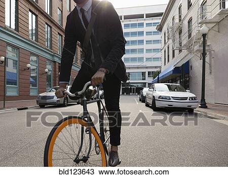 Mixed race businessman riding bicycle on city street View Large Photo Image Stock Image - Mixed race businessman riding bicycle on city street. Fotosearch