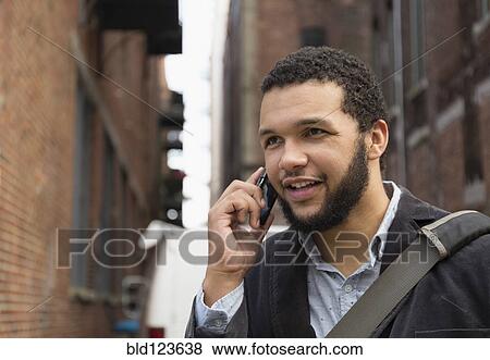 Mixed race businessman talking on cell phone in city View Large Photo Image Stock Photo - Mixed race businessman talking on cell phone in city. Fotosearch