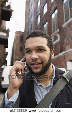 Mixed race businessman talking on cell phone in city View Large Photo Image Stock Photo - Mixed race businessman talking on cell phone in city. Fotosearch