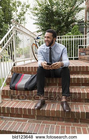 Mixed race businessman using cell phone on front stoop View Large Photo Image Stock Photo - Mixed race businessman using cell phone on front stoop. Fotosearch