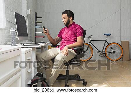 Mixed race businessman using cell phone at desk View Large Photo Image Stock Photography - Mixed race businessman using cell phone at desk. Fotosearch