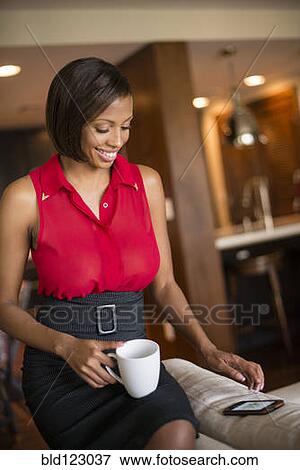 Stock Photo - Mixed race businesswoman with coffee using cell phone. Fotosearch