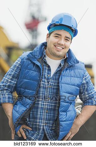 Mixed race engineer smiling at construction site View Large Photo Image Stock Photo - Mixed race engineer smiling at construction site. Fotosearch