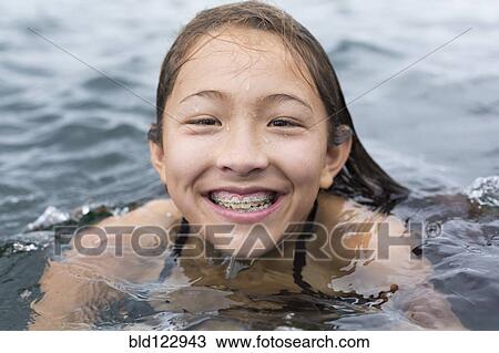 Stock Image - Mixed race girl swimming outdoors. Fotosearch
