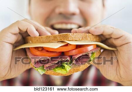 Mixed race man eating sandwich View Large Photo Image Stock Image - Mixed race man eating sandwich. Fotosearch