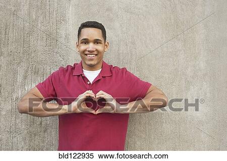 Stock Photography - Mixed race man making heart-shape with hands. Fotosearch