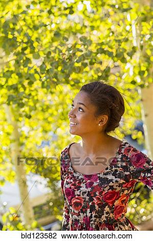 Stock Image - Mixed race teenage girl smiling outdoors. Fotosearch