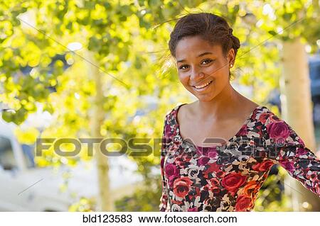 Stock Image - Mixed race teenage girl smiling outdoors. Fotosearch