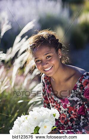 Stock Photograph - Mixed race teenage girl smiling outdoors with bouquet. Fotosearch