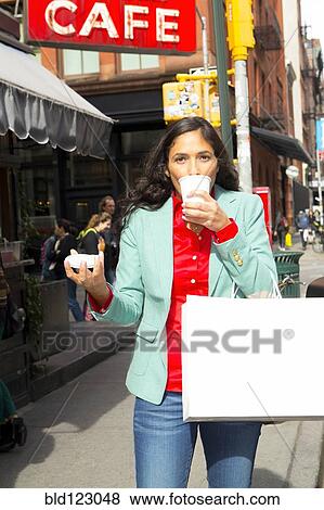 Stock Photo - Mixed race woman drinking cup of coffee in city. Fotosearch