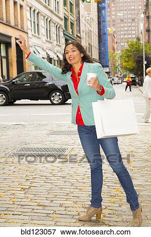 Mixed race woman hailing taxi on city street View Large Photo Image Stock Photo - Mixed race woman hailing taxi on city street. Fotosearch