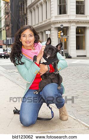 Mixed race woman holding dog on urban sidewalk View Large Photo Image Stock Image - Mixed race woman holding dog on urban sidewalk. Fotosearch