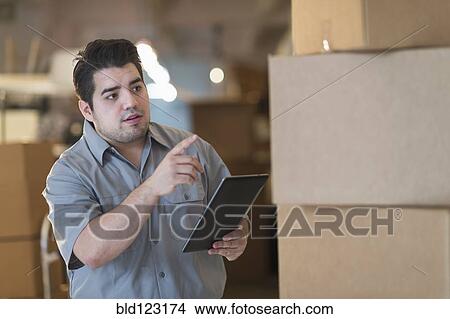 Picture - Mixed race worker counting boxes in warehouse. Fotosearch