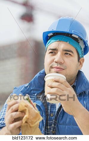 Mixed race worker eating lunch on construction site View Large Photo Image Stock Image - Mixed race worker eating lunch on construction site. Fotosearch