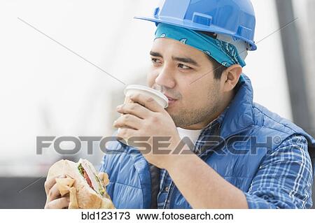 Mixed race worker eating lunch on construction site View Large Photo Image Stock Image - Mixed race worker eating lunch on construction site. Fotosearch