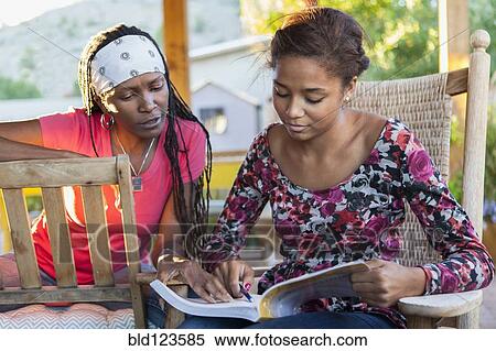 Stock Photography - Mother helping daughter with homework on patio. Fotosearch
