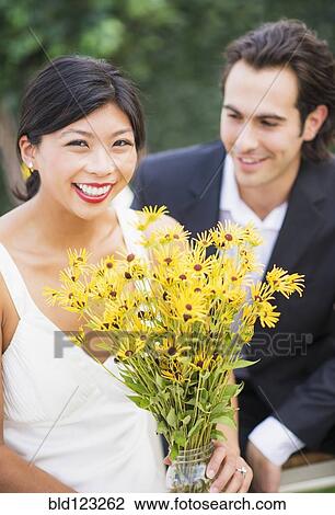 Stock Image - Newlywed couple holding bouquet. Fotosearch